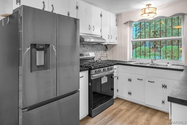 kitchen featuring wall chimney range hood, sink, light hardwood / wood-style flooring, white cabinetry, and stainless steel appliances