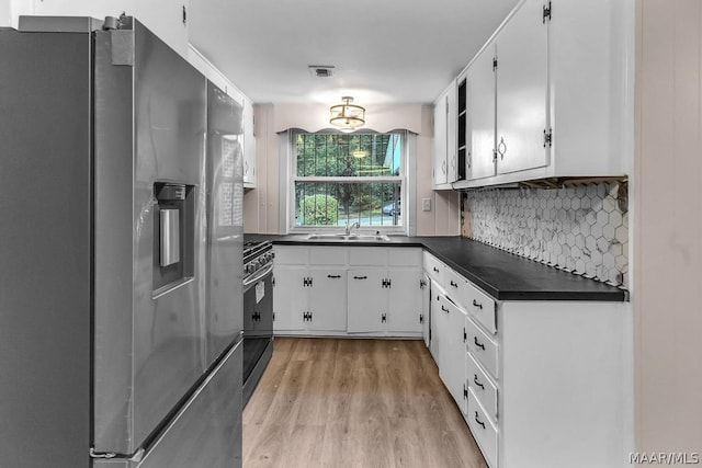 kitchen featuring sink, range, light hardwood / wood-style flooring, stainless steel fridge, and white cabinets