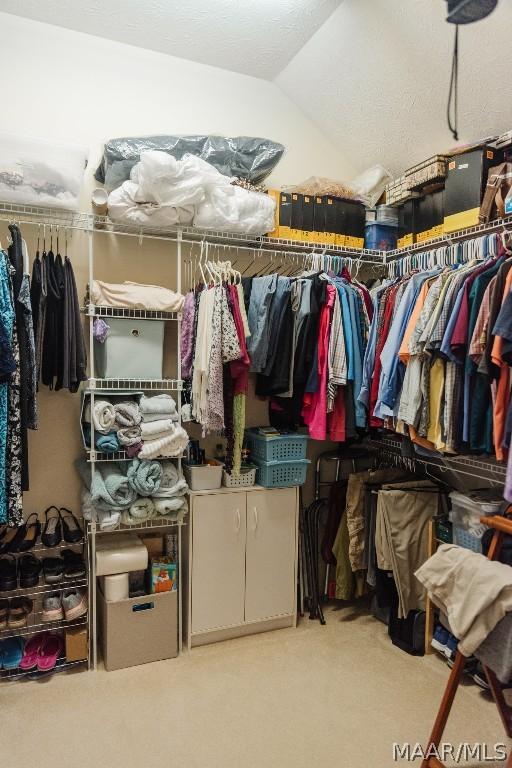 walk in closet featuring vaulted ceiling and light carpet