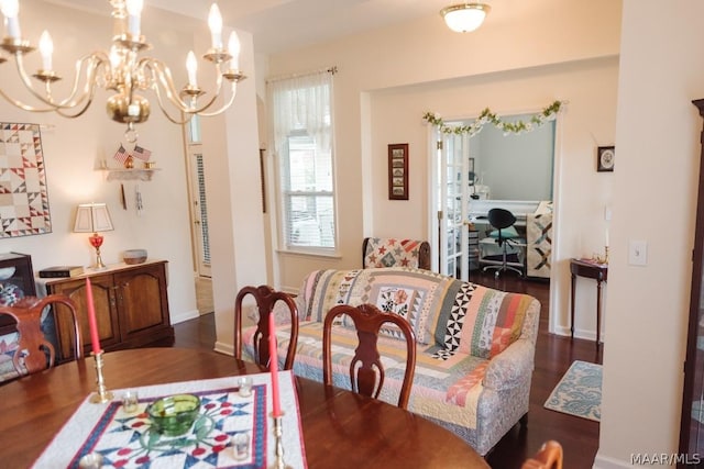 dining room with dark wood-type flooring and an inviting chandelier