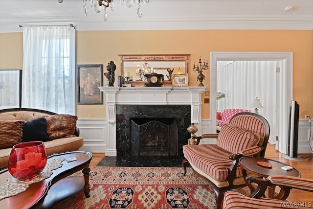 living area featuring a fireplace, wood-type flooring, and crown molding