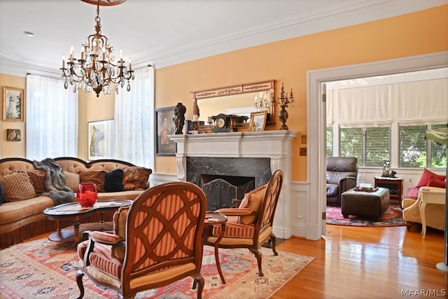 sitting room with a high end fireplace, light hardwood / wood-style floors, a chandelier, and ornamental molding