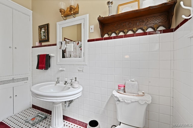 bathroom with toilet and tile walls