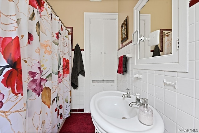 bathroom featuring a shower with shower curtain, tile walls, and sink