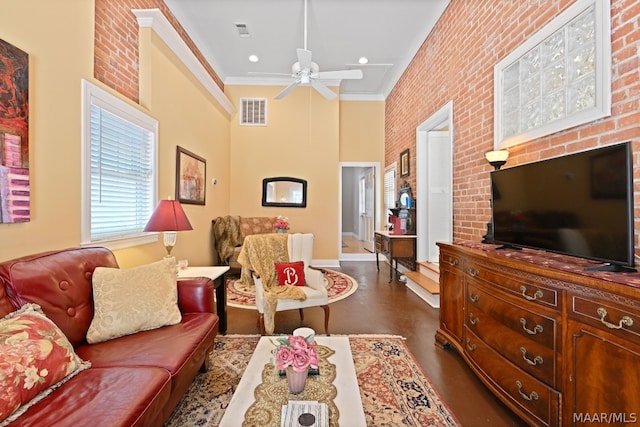 living room featuring ceiling fan, brick wall, a high ceiling, and ornamental molding