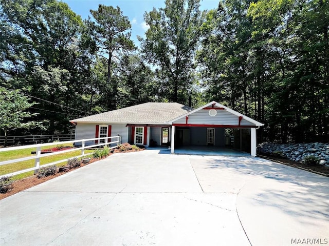 view of front of home with fence, an attached carport, and concrete driveway