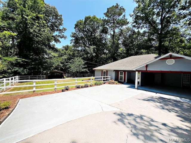 view of front of property featuring a carport, roof with shingles, driveway, and fence