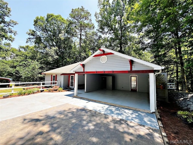 garage with driveway, fence, and an attached carport