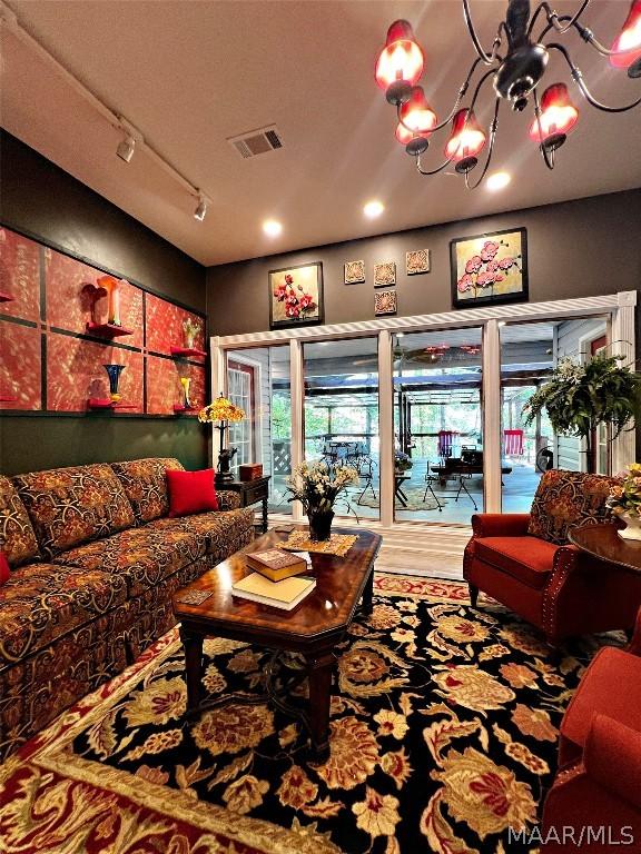 living room featuring a textured ceiling, hardwood / wood-style flooring, track lighting, and a chandelier