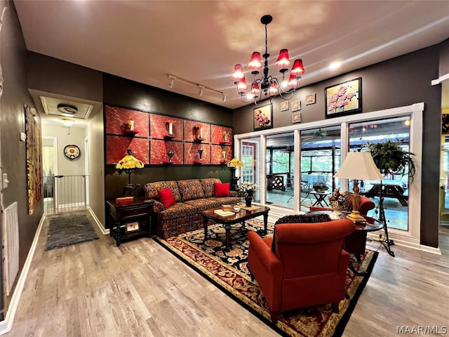 living room featuring a chandelier, light wood finished floors, attic access, and track lighting