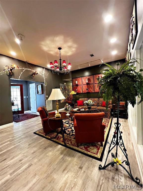 living room with a notable chandelier, track lighting, and light wood-type flooring