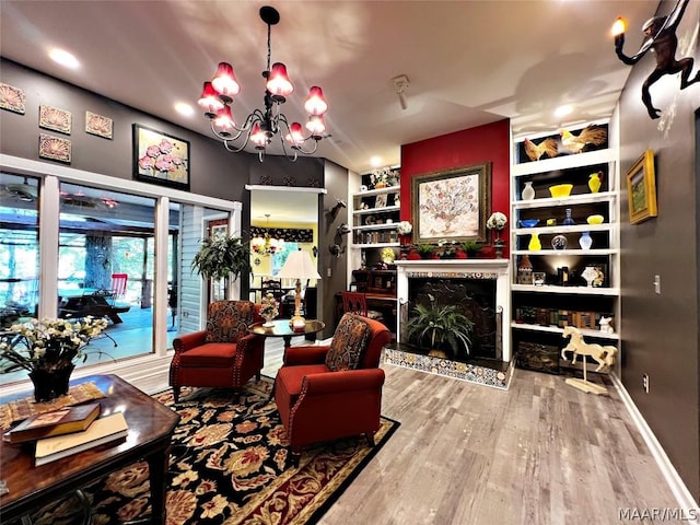 living room featuring built in features, a fireplace, a chandelier, and wood finished floors