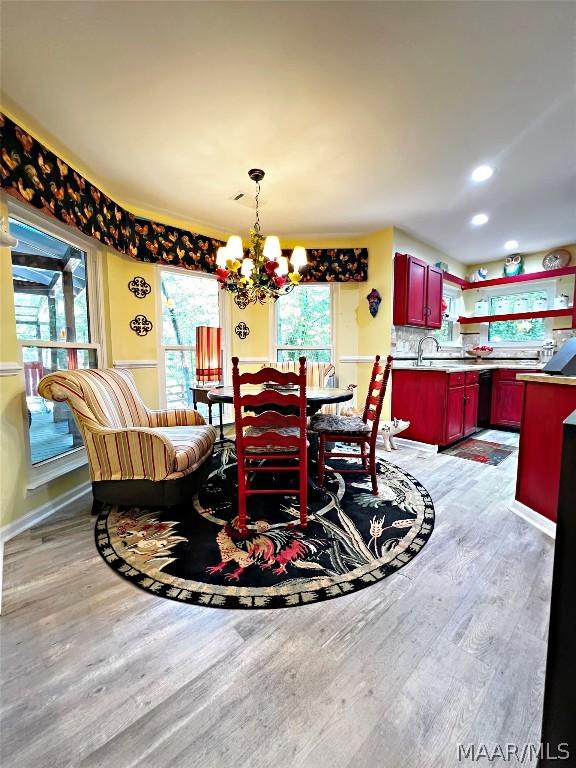 dining room featuring sink, hardwood / wood-style flooring, and an inviting chandelier