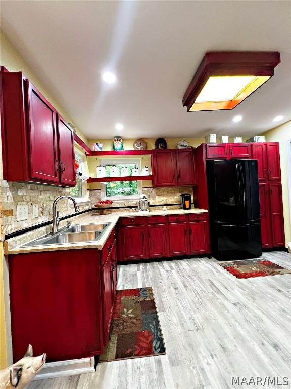 kitchen featuring a sink, light countertops, backsplash, freestanding refrigerator, and open shelves