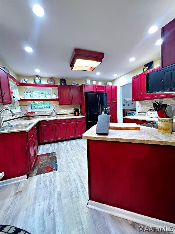 kitchen with black fridge, sink, tasteful backsplash, and light hardwood / wood-style flooring