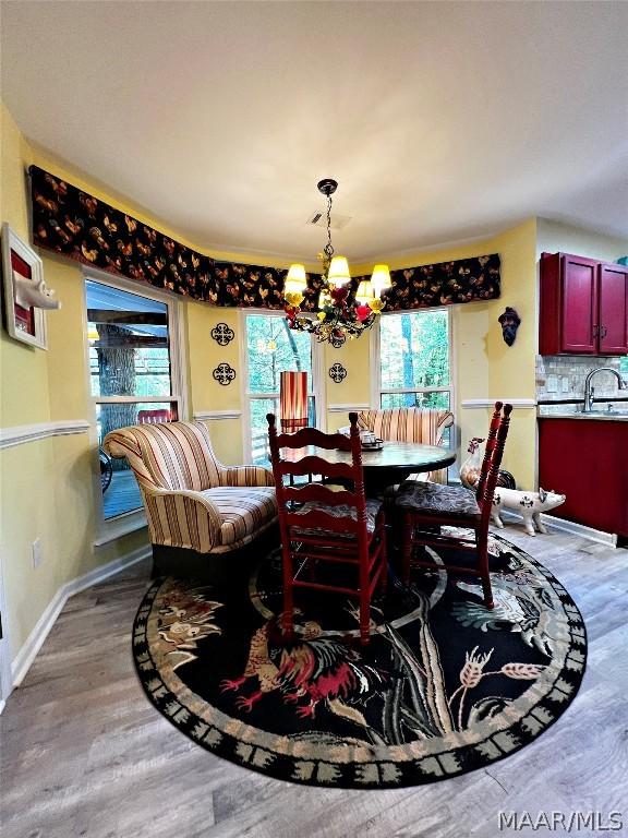 dining room with sink, a chandelier, and hardwood / wood-style flooring