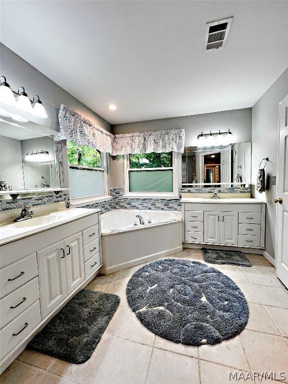 bathroom featuring tile flooring, dual vanity, and a tub