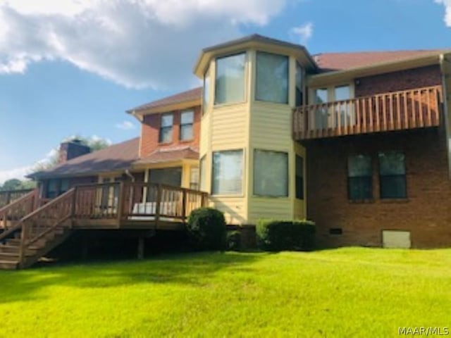 rear view of property with a wooden deck and a lawn