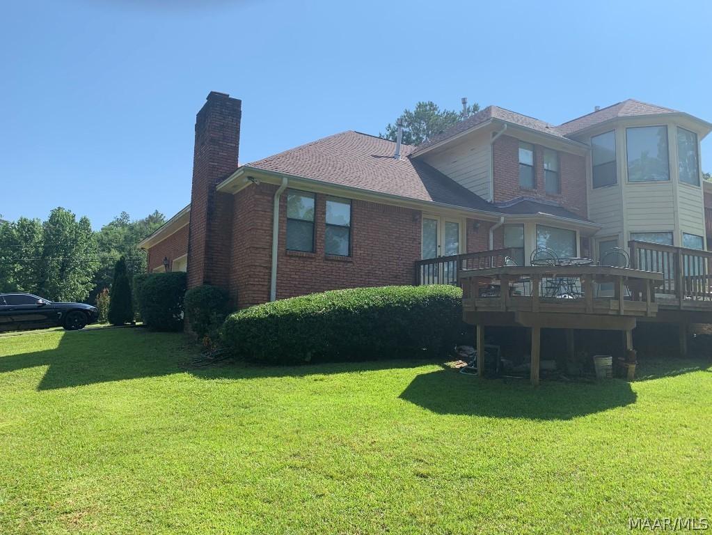 rear view of house with a yard and a wooden deck