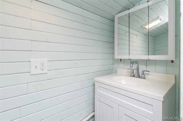 bathroom featuring wooden walls, vanity, and lofted ceiling