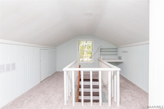 bonus room featuring light carpet, vaulted ceiling, and wooden walls