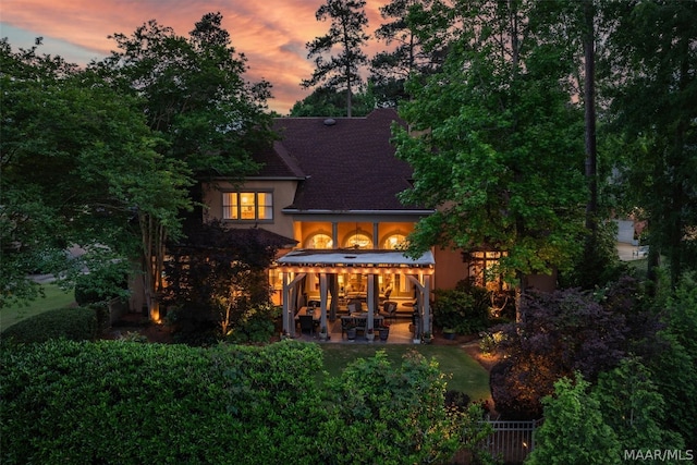 back house at dusk with a patio area