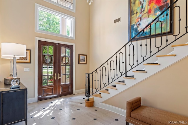 entryway with a high ceiling, french doors, and tile floors