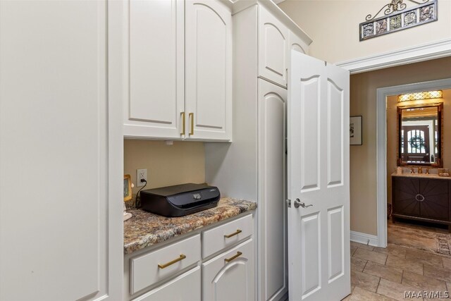 kitchen featuring sink, white cabinetry, light tile flooring, and light stone countertops