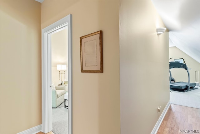 hallway with hardwood / wood-style flooring and vaulted ceiling