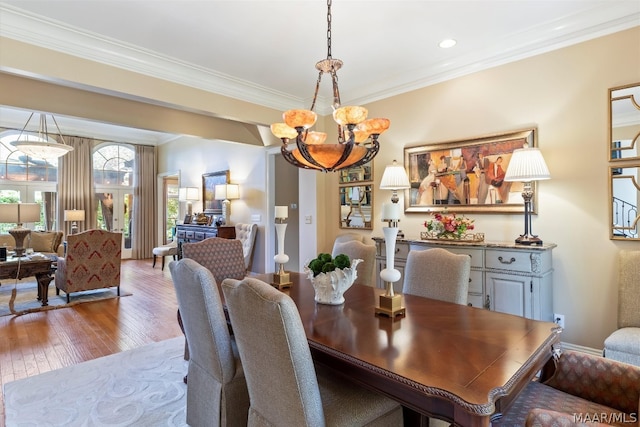 dining space featuring ornamental molding, hardwood / wood-style flooring, and a chandelier