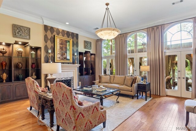 living room with french doors, ornamental molding, and light wood-type flooring