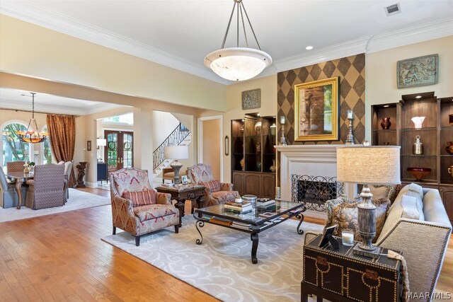 living room with an inviting chandelier, hardwood / wood-style flooring, and crown molding