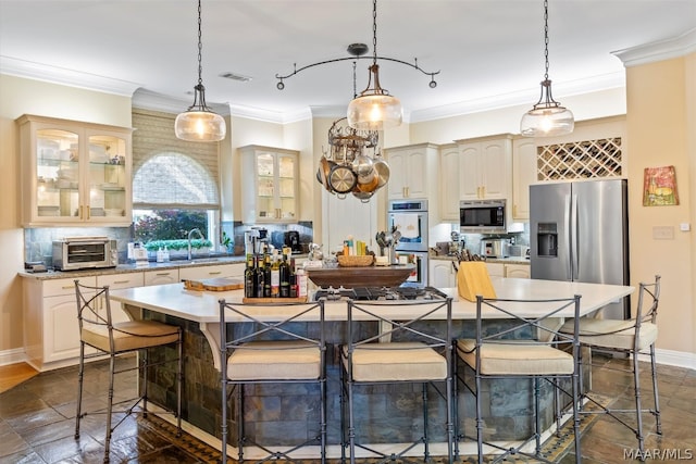 kitchen featuring crown molding, a kitchen island, stainless steel appliances, a breakfast bar area, and backsplash