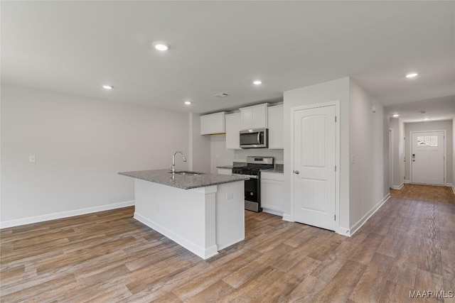 kitchen featuring sink, light hardwood / wood-style flooring, a center island with sink, white cabinets, and appliances with stainless steel finishes