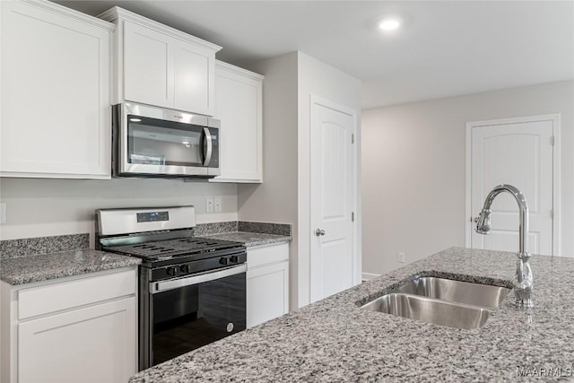 kitchen featuring white cabinets, stainless steel appliances, light stone countertops, and sink