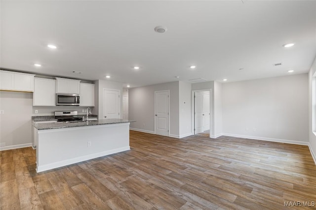 kitchen with a center island with sink, light hardwood / wood-style floors, white cabinets, and appliances with stainless steel finishes