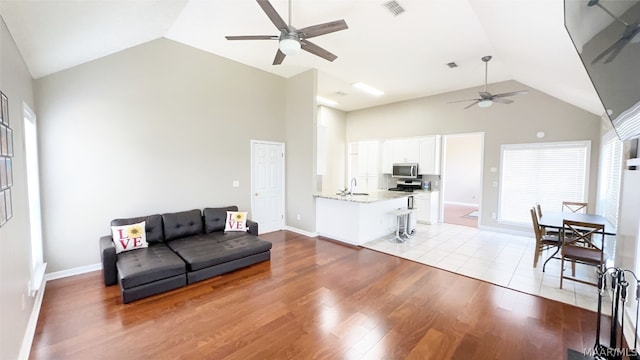 living room featuring high vaulted ceiling, ceiling fan, and light tile flooring