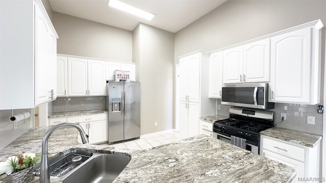 kitchen with appliances with stainless steel finishes, sink, tasteful backsplash, and light stone counters