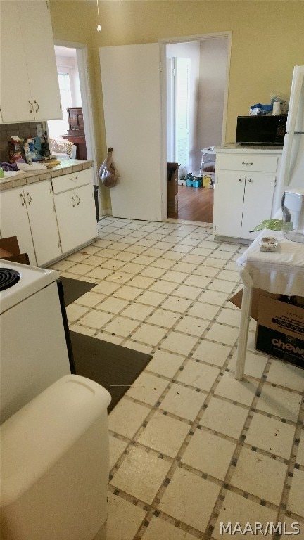 kitchen featuring white cabinetry and white fridge