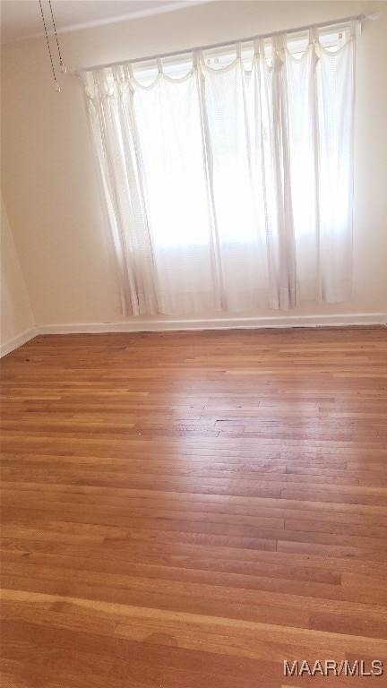 empty room with light wood finished floors and baseboards