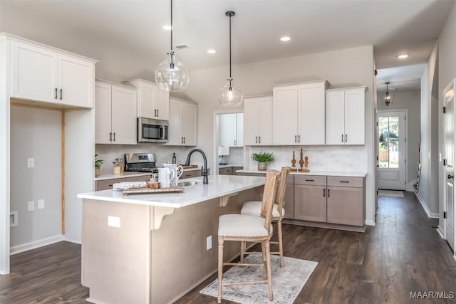 kitchen featuring stainless steel appliances, tasteful backsplash, dark wood-style flooring, and light countertops