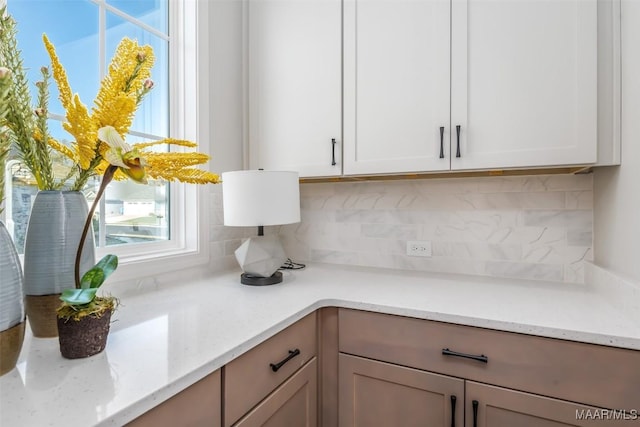 kitchen with light stone countertops, white cabinets, and decorative backsplash