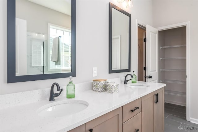 full bath with double vanity, a walk in closet, and a sink