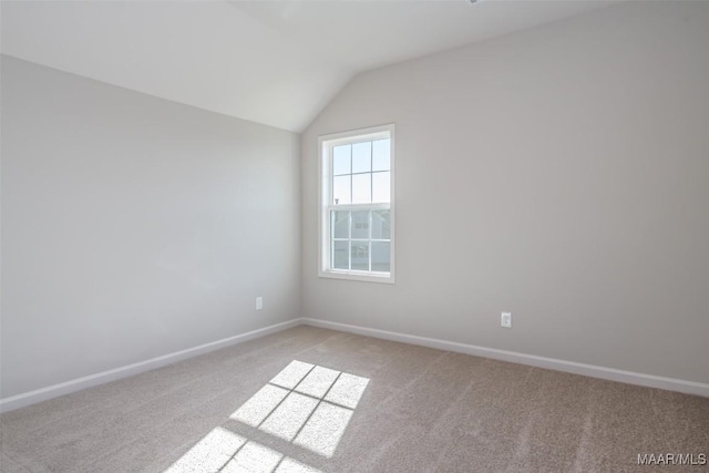 spare room with lofted ceiling, light colored carpet, and baseboards