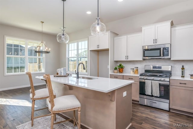 kitchen featuring dark wood finished floors, a sink, stainless steel appliances, light countertops, and backsplash