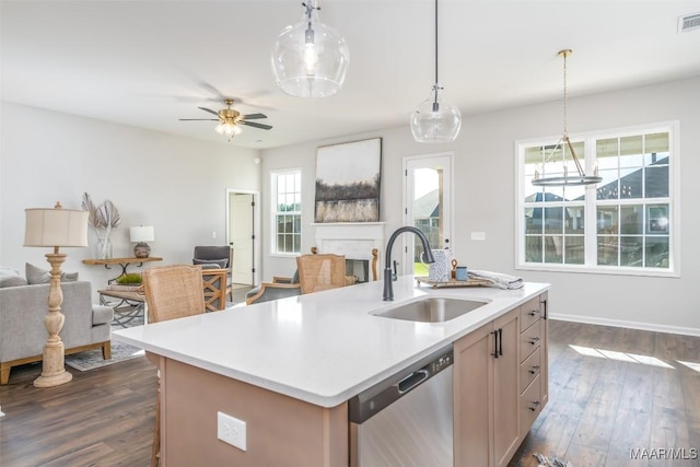 kitchen featuring open floor plan, dark wood-style flooring, stainless steel dishwasher, a fireplace, and a sink