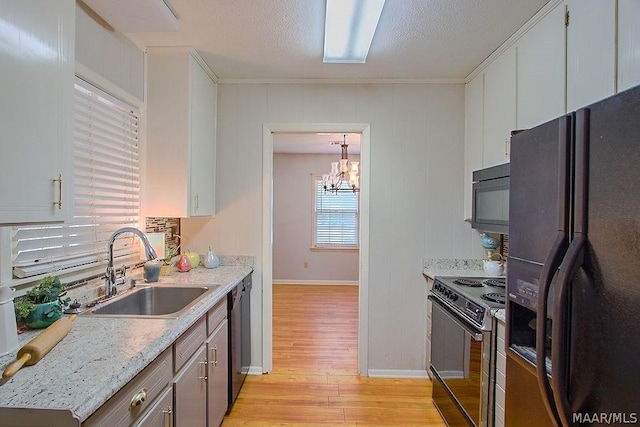 kitchen featuring light stone countertops, sink, black appliances, pendant lighting, and a notable chandelier