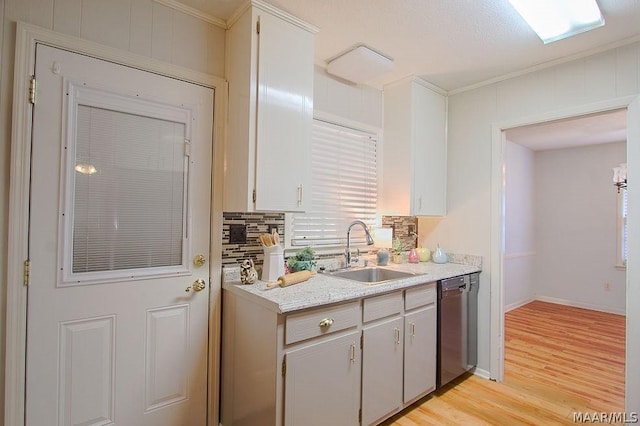 kitchen with sink, stainless steel dishwasher, light wood-type flooring, and ornamental molding