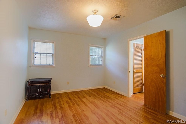 unfurnished room featuring light hardwood / wood-style floors and a textured ceiling