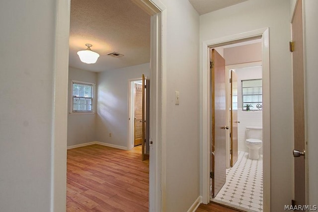 corridor featuring a textured ceiling and light wood-type flooring